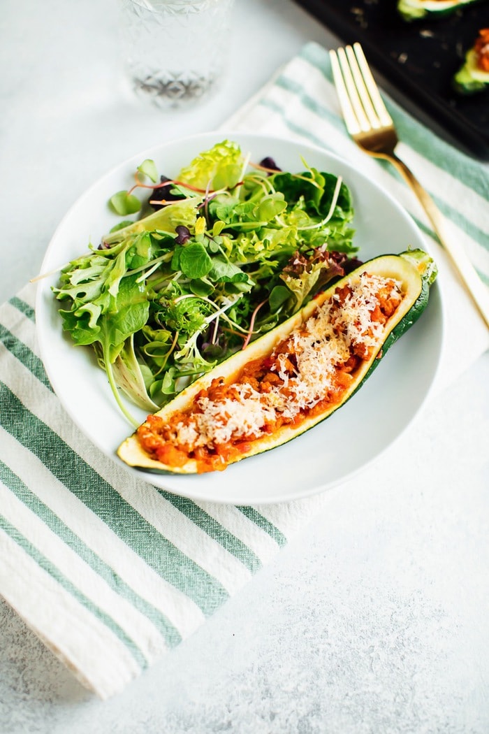 One turkey zucchini boat on a plate with salad. 