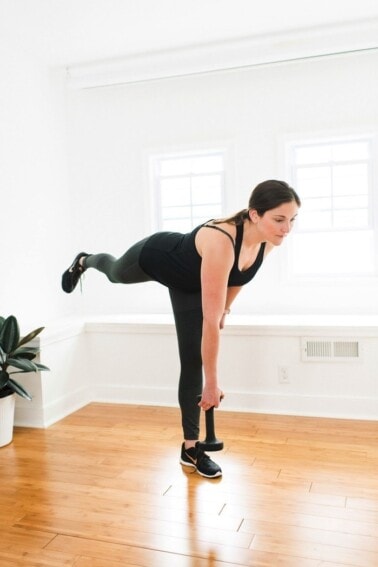 Woman in black workout attire doing a single leg deadlift.