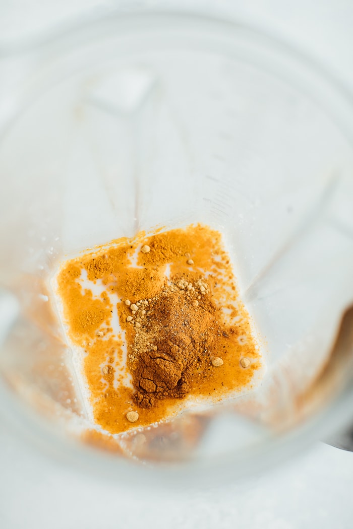 All the ingredients for a Golden Milk Smoothie in the blender with ginger, turmeric and cinnamon on top. All the ingredients for a Golden Milk Smoothie in the blender with ginger, turmeric and cinnamon on top.