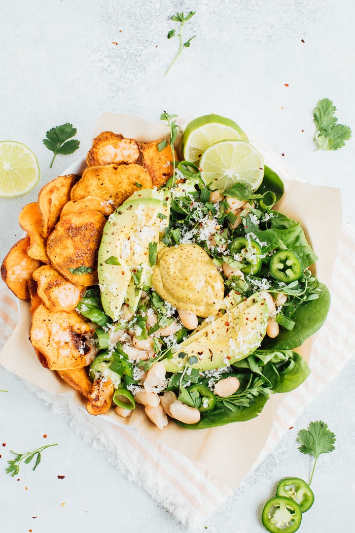 Loaded sweet potato nacho salad bowls bowls with sweet potato chips, baby spinach, jalapeño and fresh herbs. 