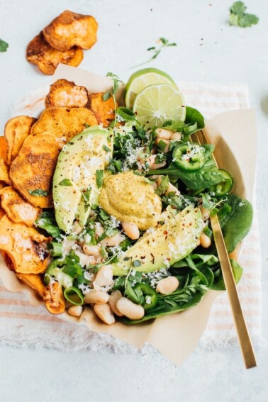 Loaded sweet potato nacho salad bowls bowls with sweet potato chips, baby spinach, jalapeño and fresh herbs.