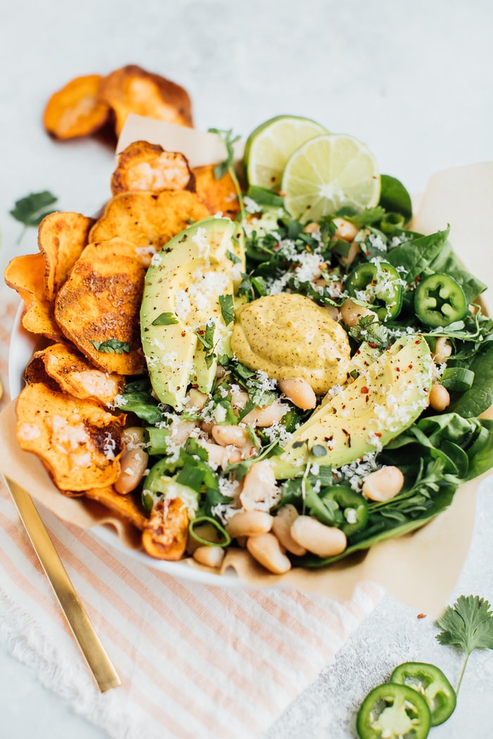 Loaded sweet potato nacho salad bowls bowls with sweet potato chips, baby spinach, jalapeño and fresh herbs. 