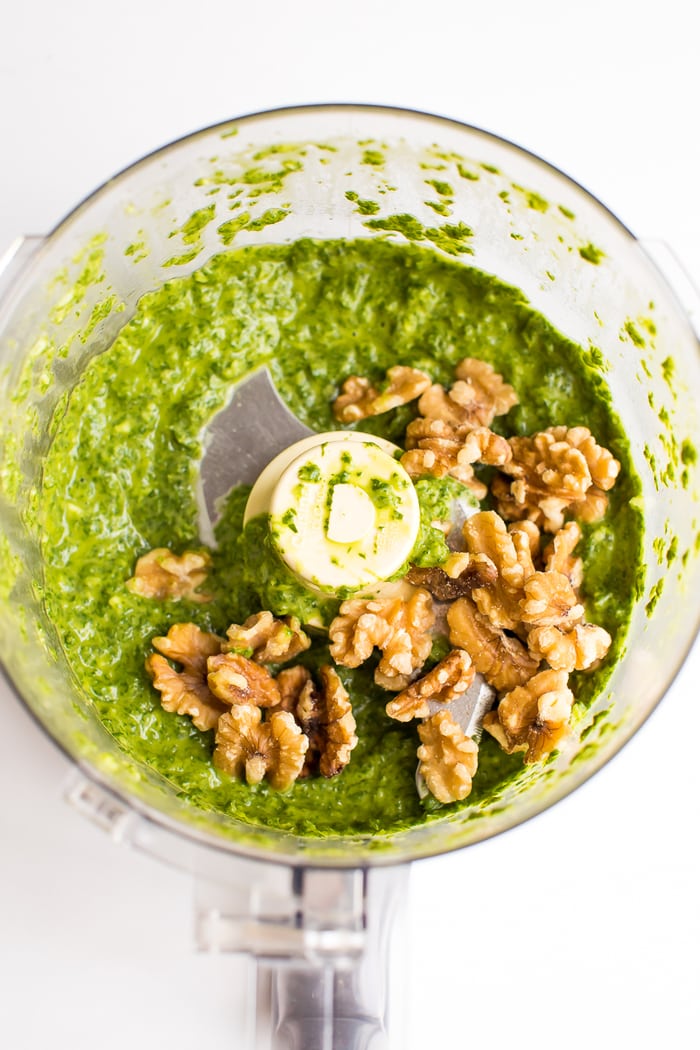 Top down view of pesto and walnuts in a food processor.