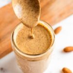 Spoon dipping into almond dressing in a jar.