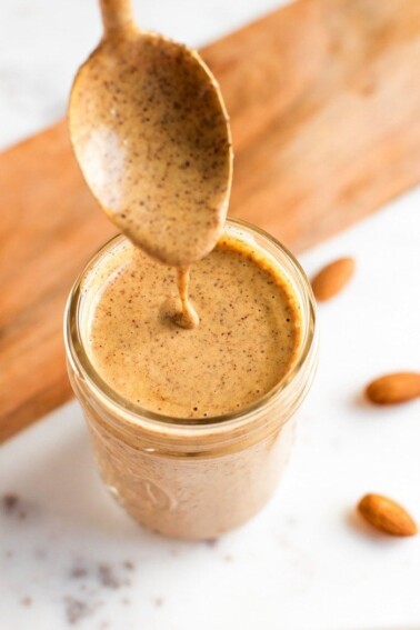 Spoon dipping into almond dressing in a jar.