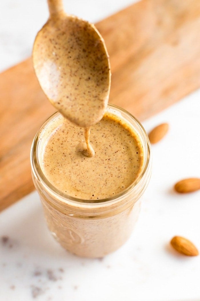 Chili almond dressing in a mason jar with gold spoon. 