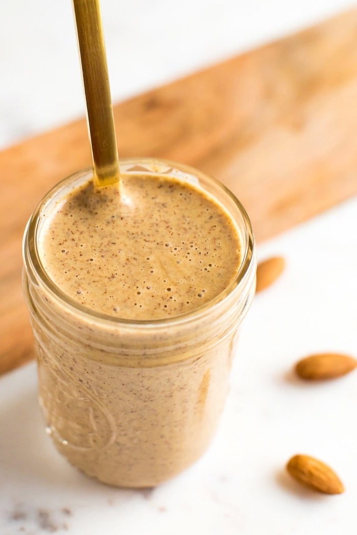 PIN THIS --> Chili Almond Dressing Almond dressing in a mason jar with gold spoon.