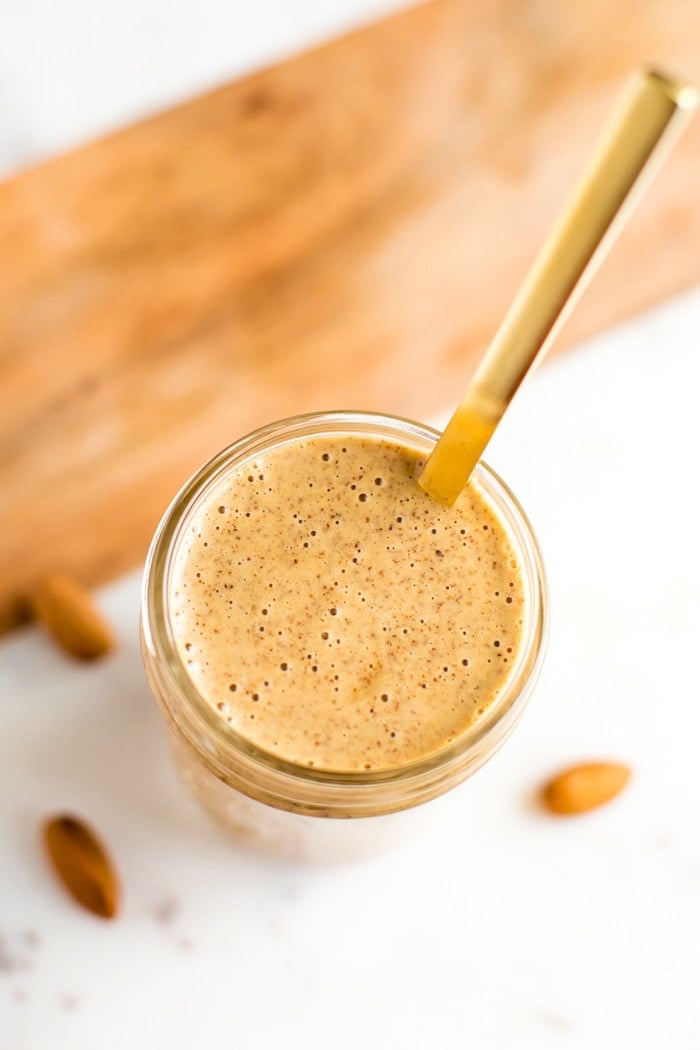 PIN THiS --> Chili Almond Dressing Chili almond dressing a small mason jar with gold spoon. Almonds in background.
