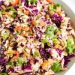 Asian chopped salad in a white bowl with chopped almonds on top.