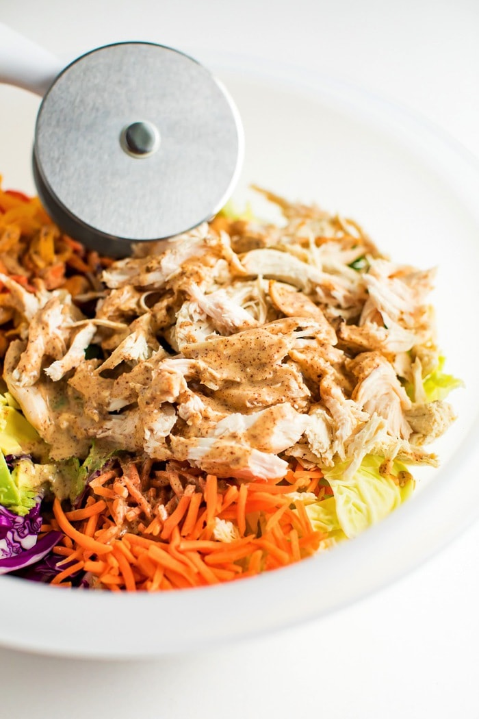 All the ingredients for an Asian chopped salad in a large salad chopper bowl. 