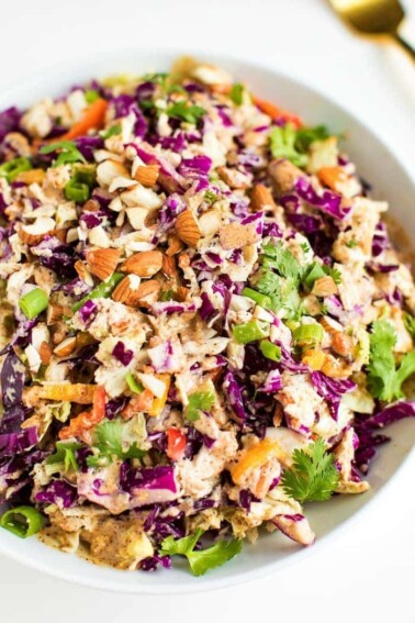 Asian chopped salad in a white bowl with chopped almonds on top.