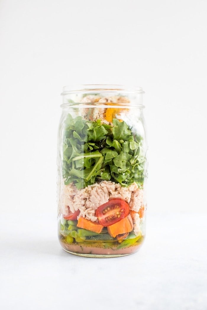 Mason jar salad layered with green beans, asparagus, roasted potatoes, tomatoes, olives, tuna, arugula, hard boiled egg and fresh dill. 