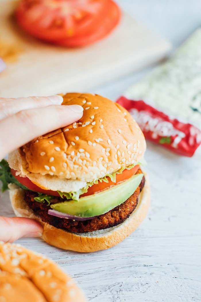 Tempeh burger with avocado being picked up. 