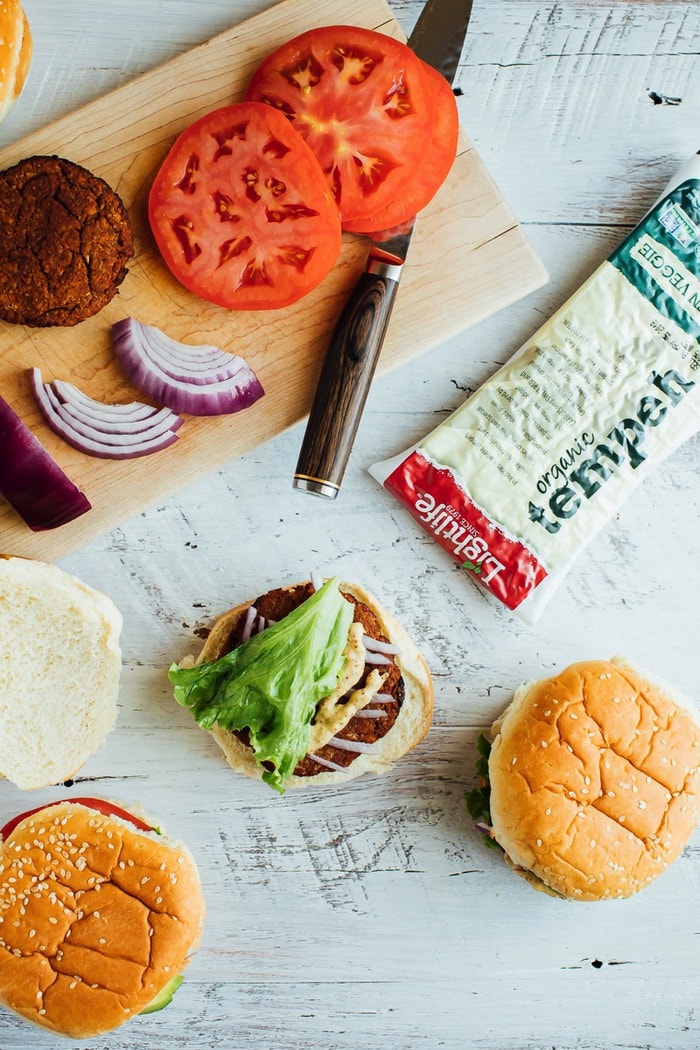 Tempeh burger spread laid out with toppings and tempeh package. 