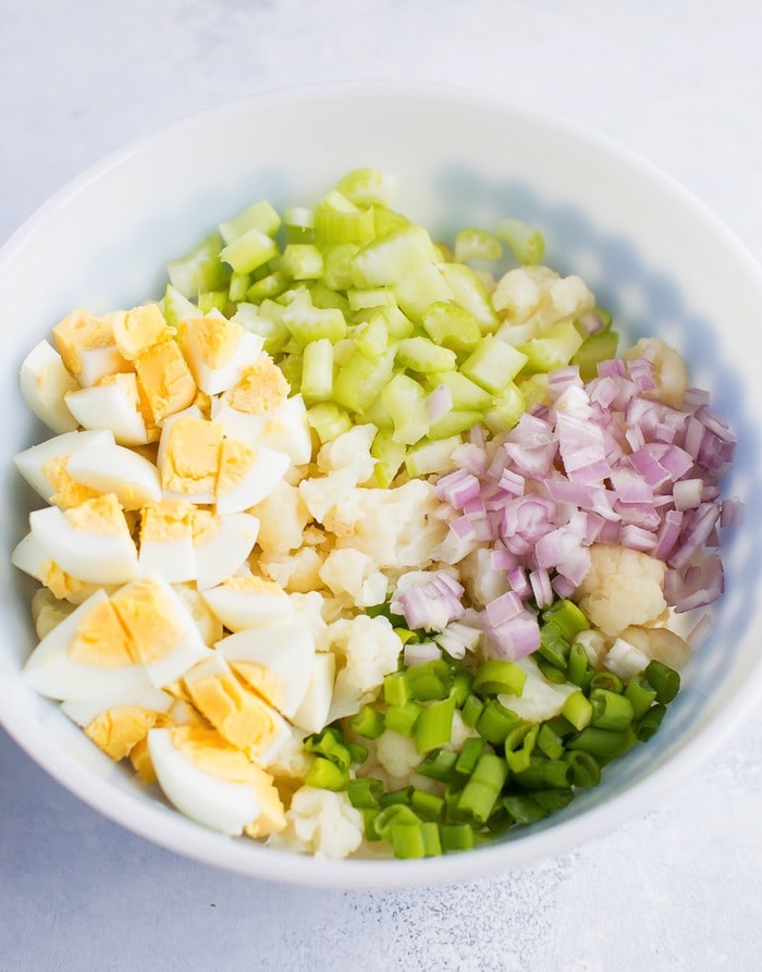 Cauliflower potato salad ingredients in a large bowl before mixing. 