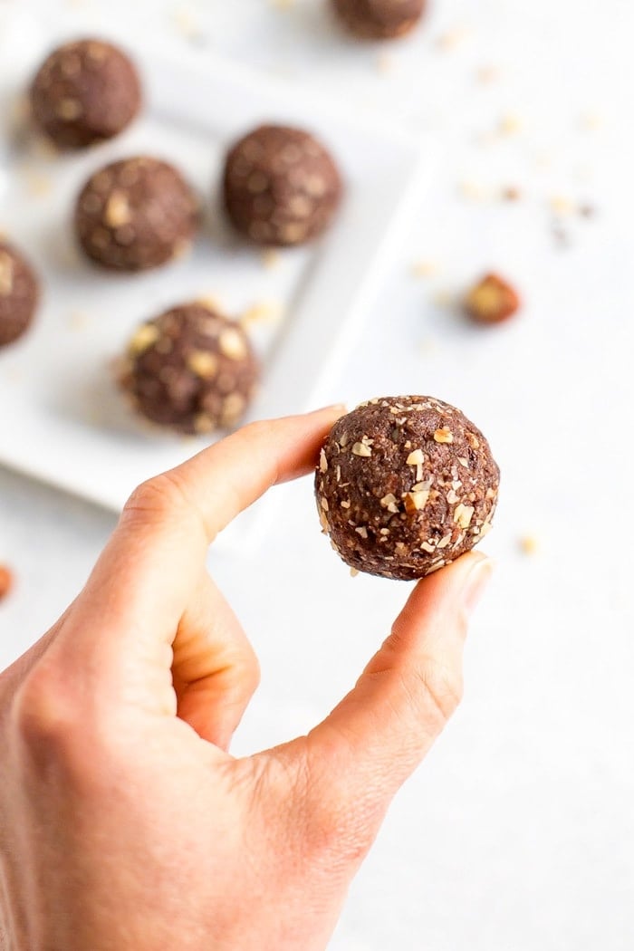 Homemade chocolate hazelnut energy bite being held by a woman's hand. 