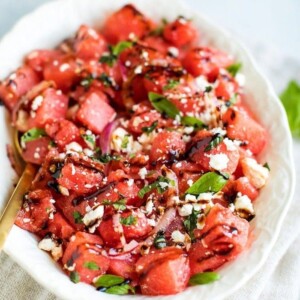 Watermelon Feta Salad with Balsamic Reduction in a white serving dish on top of a natural tan napkin.