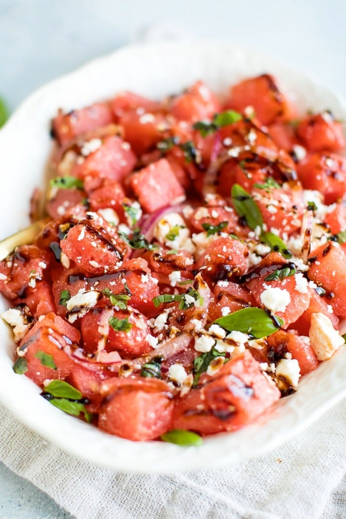 Watermelon Feta Salad with Balsamic Reduction in a white serving dish on top of a natural tan napkin. 