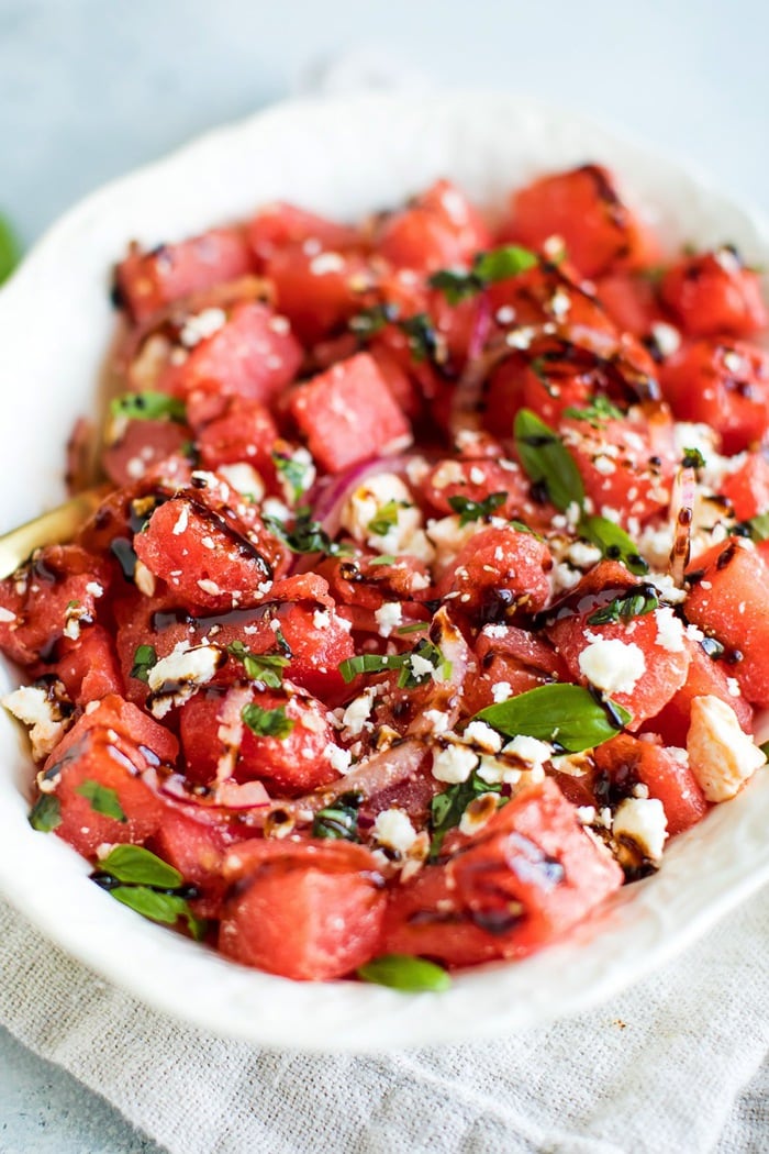 Watermelon Feta Salad with Balsamic Reduction in a white serving dish on top of a natural tan napkin. 