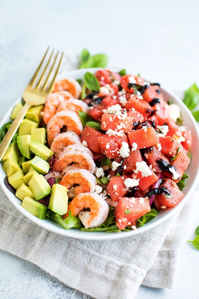 A large salad bowl with watermelon feta salad, grilled shrimp and avocado. 