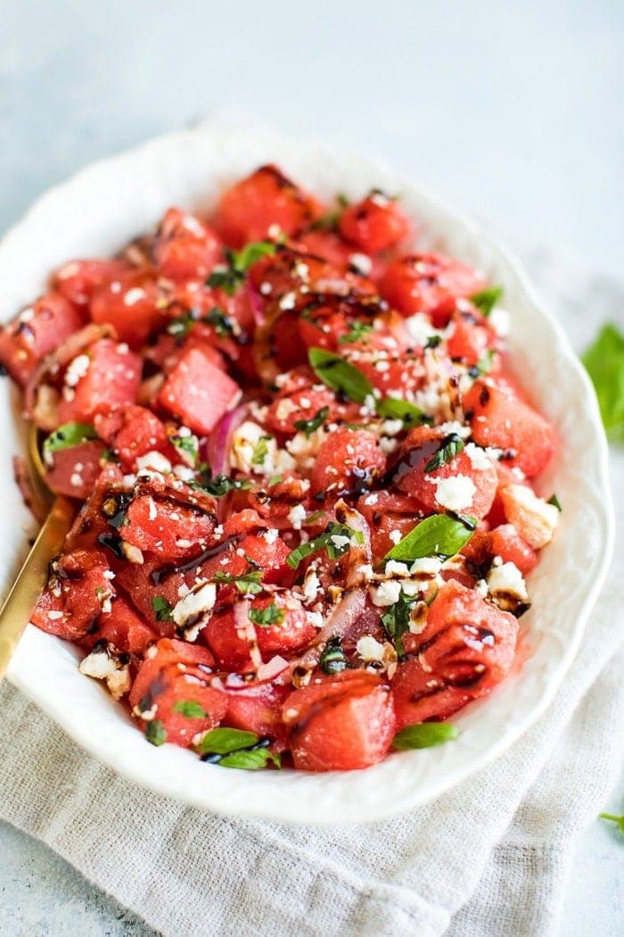 Watermelon Feta Salad with Balsamic Reduction in a white serving dish on top of a natural tan napkin. 