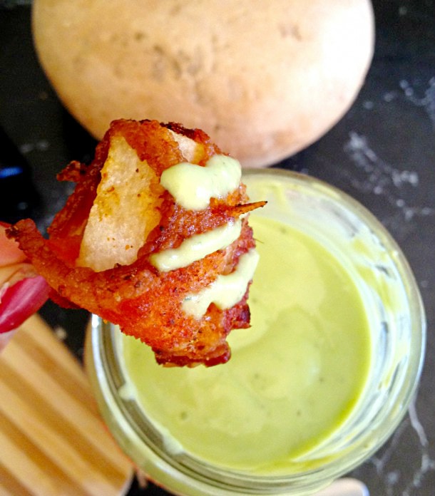 Hand dipping bacon wrapped jicama into a creamy dip.