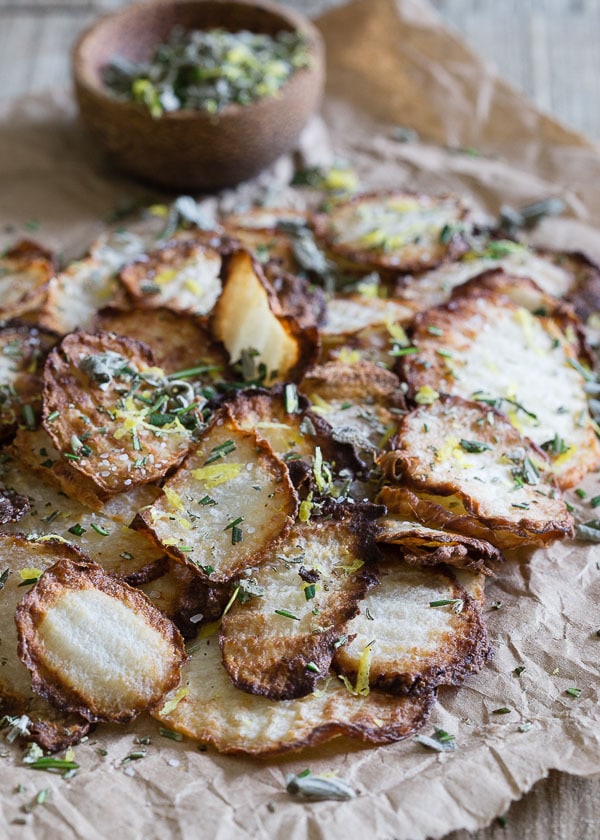 Crispy jicama baked chips on parchment paper and sprinkled with salt and herbs.