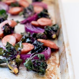 Sheet pan with baked chicken sausage, kale, and red onion.