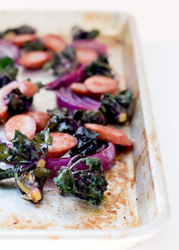 Sheet pan with baked chicken sausage, kale, and red onion.