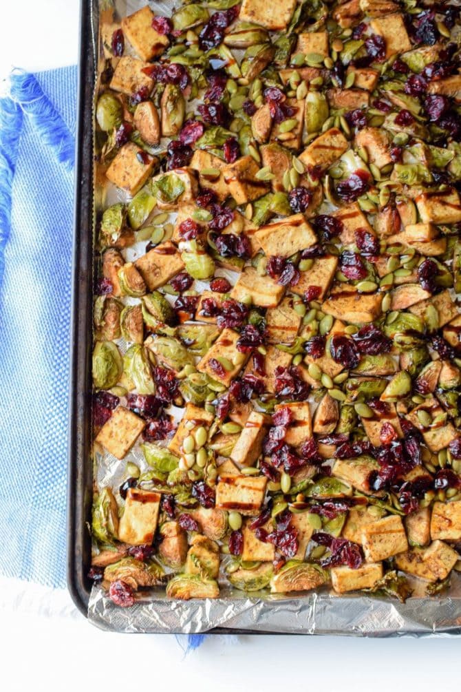 Sheet pan with baked garlic tofu and Brussels topped with pumpkin seeds and craisins.