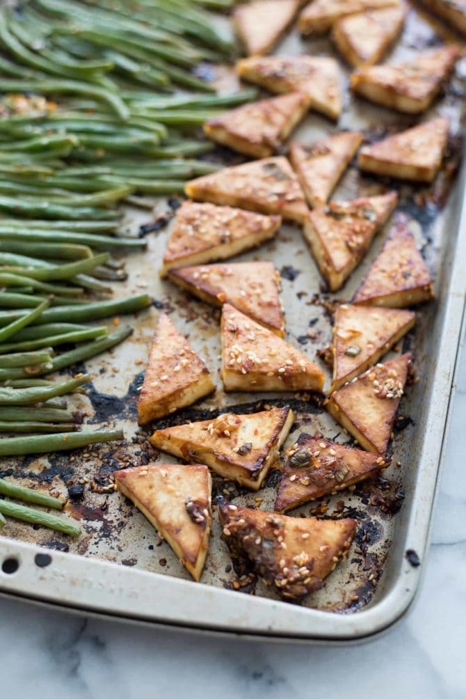 Sheet pan with baked spicy tofu and green beans.