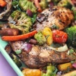 Sheet pan with baked balsamic chicken and broccoli, peppers, tomatoes, and herbs.