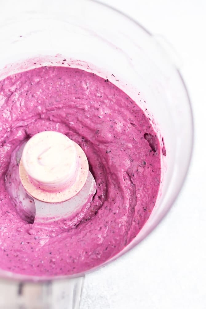 Food processed filled with blueberry frozen yogurt that is being blended up.