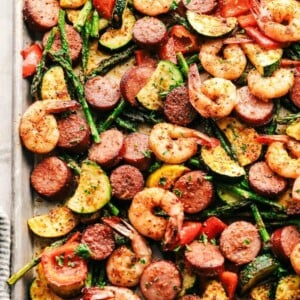 Sheet pan with cajun shrimp, sliced sausage, asparagus, zucchini and squash.