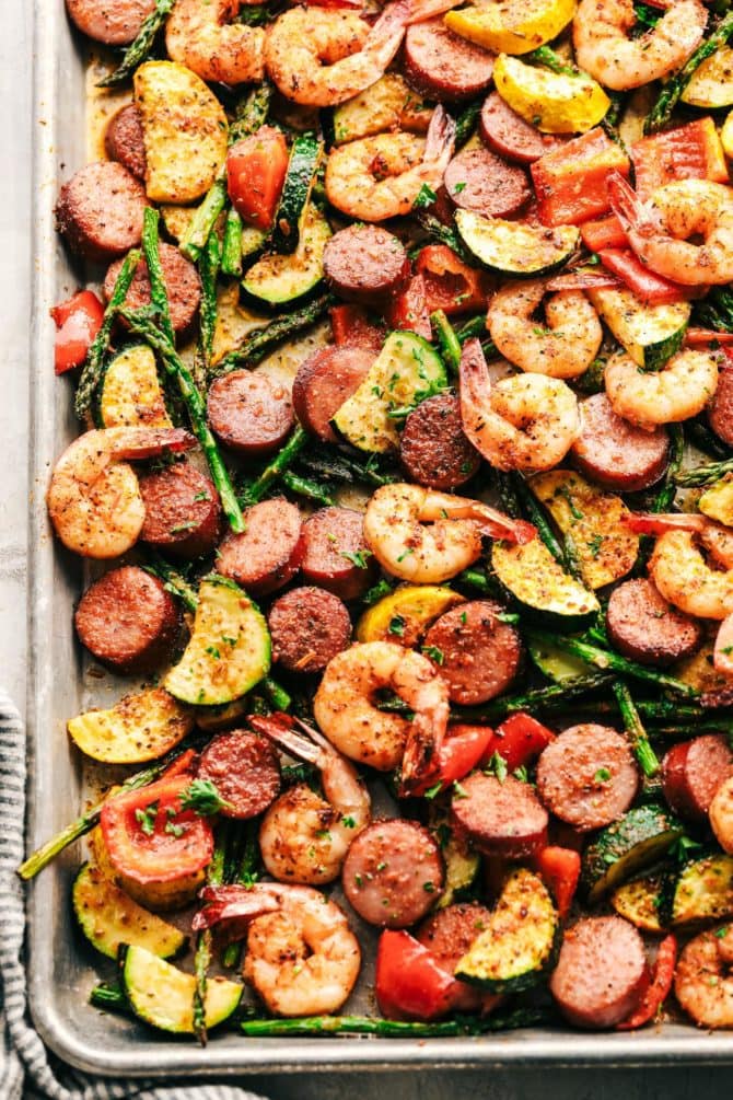 Sheet pan with cajun shrimp, sliced sausage, asparagus, zucchini and squash.