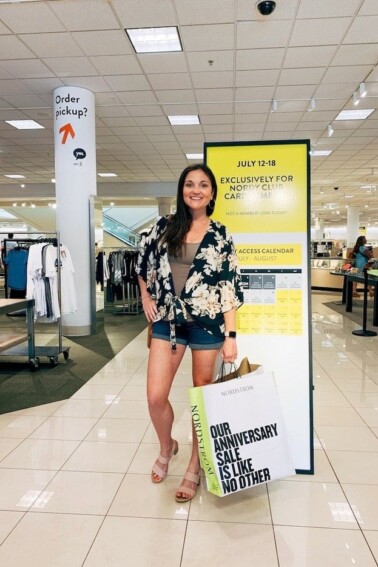 Woman smiling with Nordstrom shopping bag in Nordstrom.