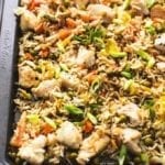 Sheet pan with baked chicken pieces, fried rice, scallions and mini pieces of carrots.
