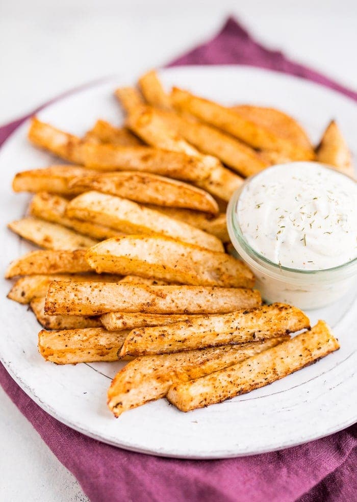 White plate piled with turnip fries and a greek yogurt ranch dip in a glass jar.