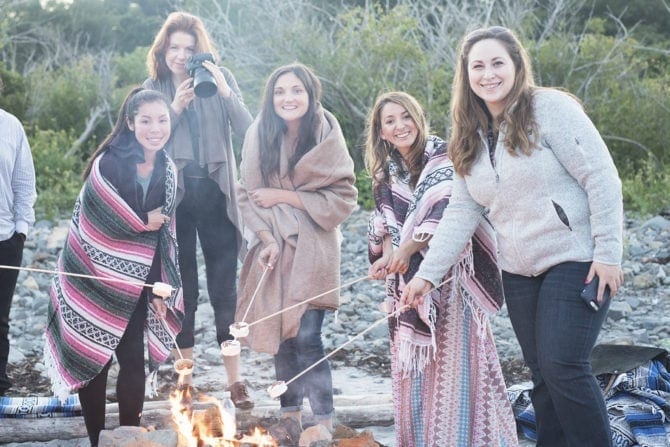 PIN THIS--> A Trip to York, Maine A group fo 5 woman roasting marshmallows on a beach, wrapped in patterned blankets.