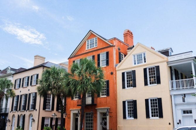 Row of brightly painted houses in Charleston, SC. Palm trees in front.