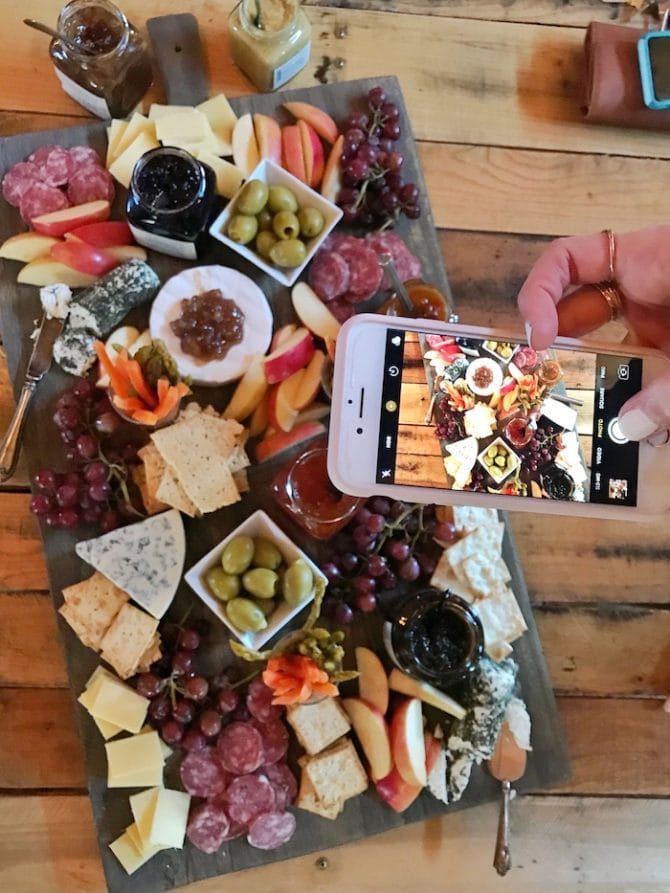 PIN THIS--> A Trip to York, Maine Woman taking a iPhone photo of a cheese, meat, and fruit platter.