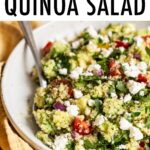 Bowl of quinoa salad with feta, spinach and tomatoes.