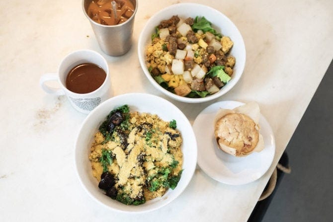 Two breakfast burritos in a bowl, a plate with a muffin, and two mugs of coffee, one hot one iced. Gnome Cafe Charleston, SC.