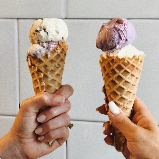 Two women's hands holding cones from Jeni's ice cream in Charleston, SC.