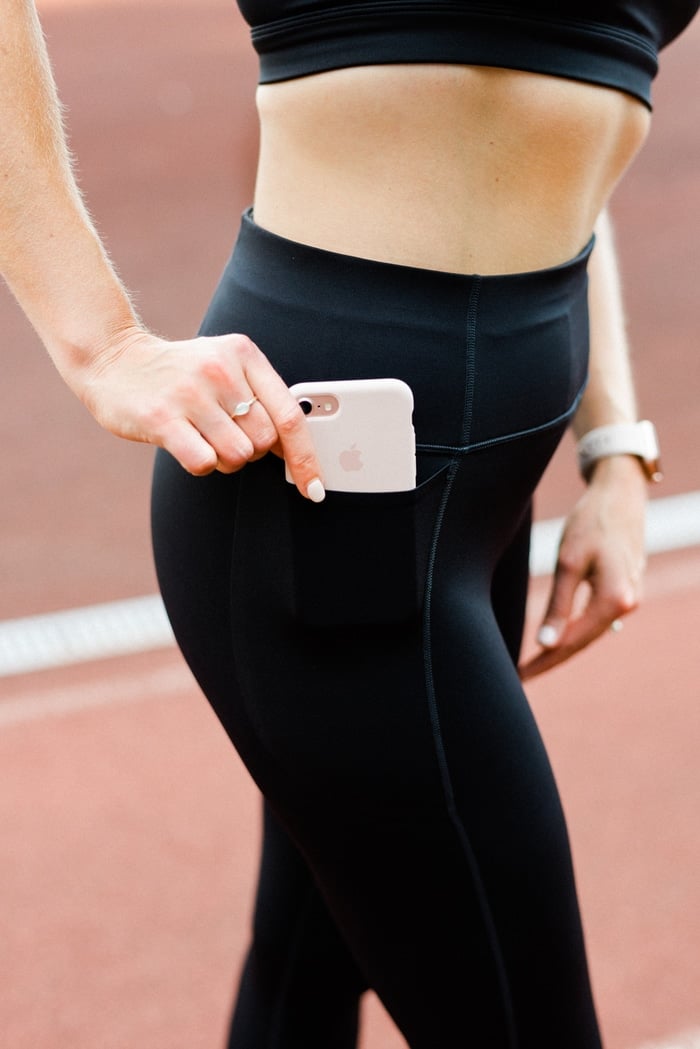 Women in black running tights pulling her phone from a pocket.