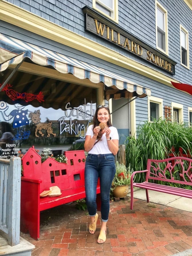 PIN THIS--> A Trip to York, ME and Portland, ME Woman in a t-shirt and jeans standing outside of a bake shop holding a cookie.