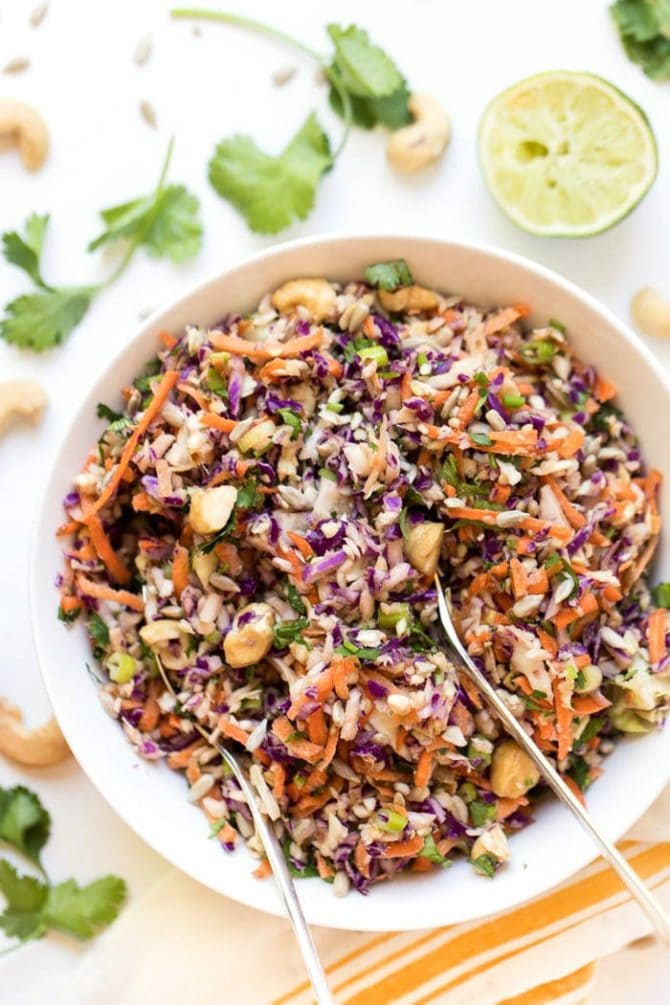 Curry Roasted Fennel Salad with Rosemary Tahini Dressing in a bowl. Cilantro, line and cashews are to the side.