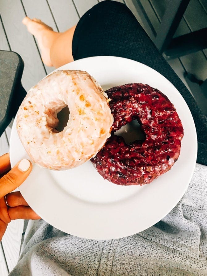 PIN THIS--> A Trip to York, ME and Portland, ME Woman holding a plate with two donuts, one chocolate sea salt, one blueberry.
