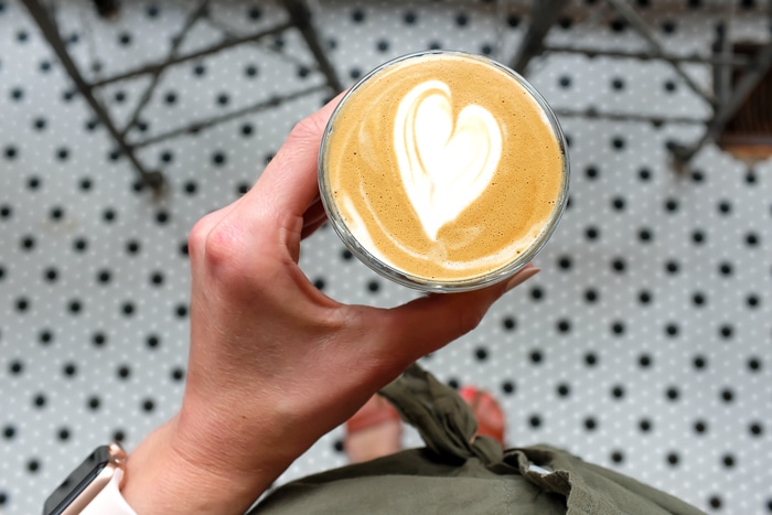 Woman holding a almond milk latte at a bird's-eye view.