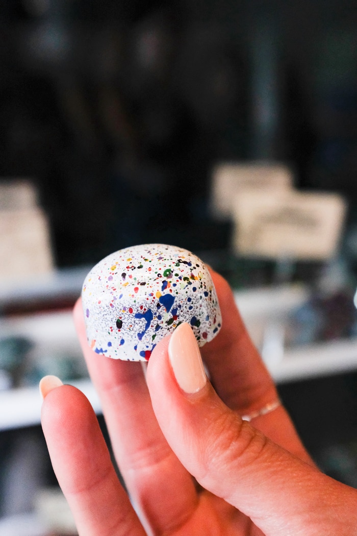 Woman's hand holding a marbled, colorful truffle.